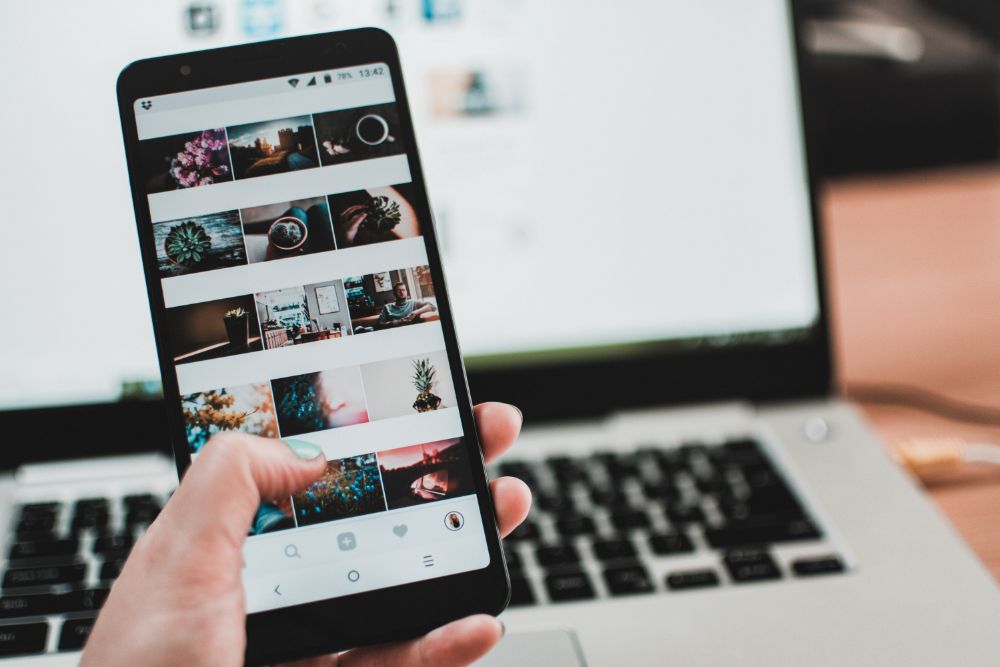 a woman's hand searches through photos on her cell phone. 