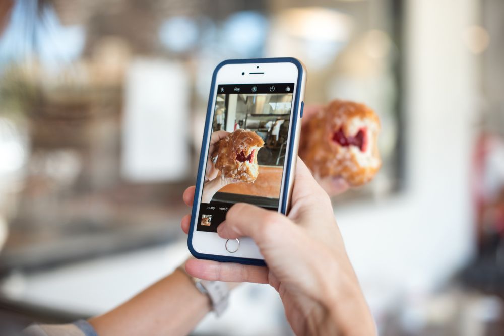 A person takes a photo fo their tasty breakfast pastry. Your customers can be a great source of images. Photo by Callie Morgan on Unsplash